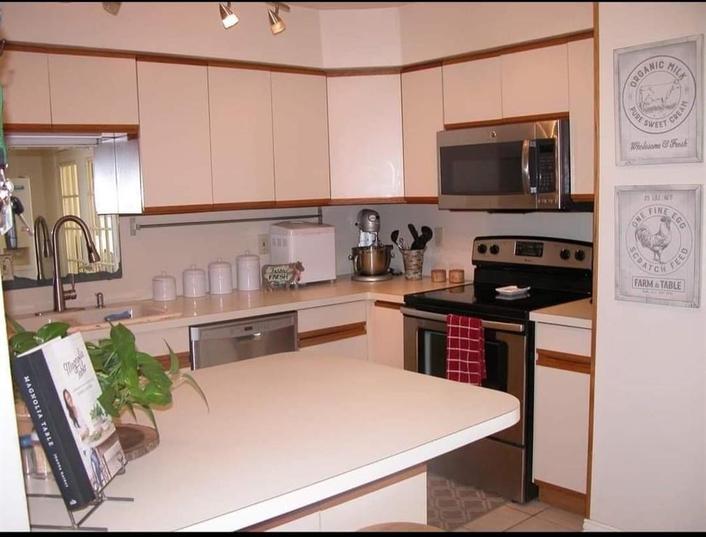 a kitchen with stainless steel appliances kitchen island granite countertop a sink a stove and a microwave