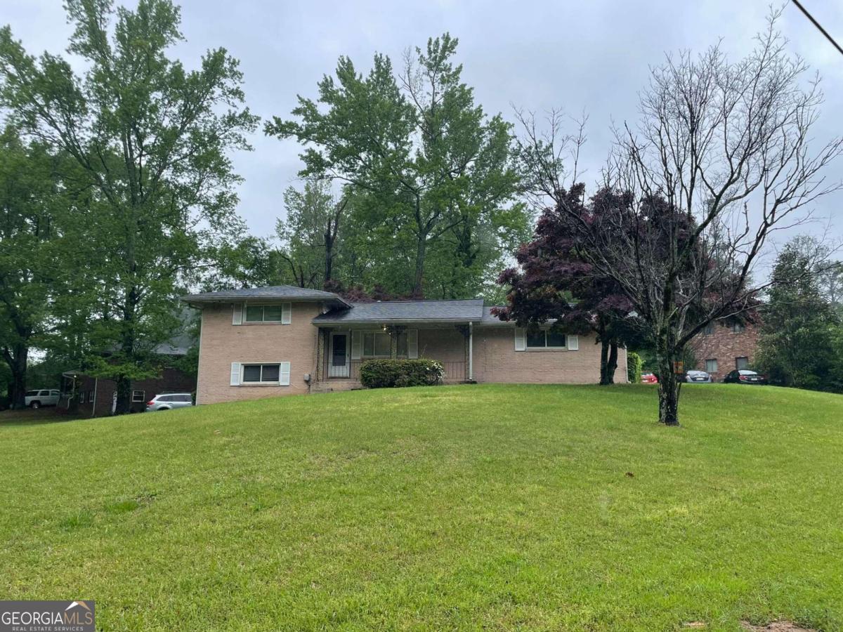 a house that is sitting in the grass with large trees