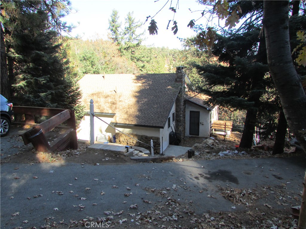 a view of a house with large tree and wooden fence