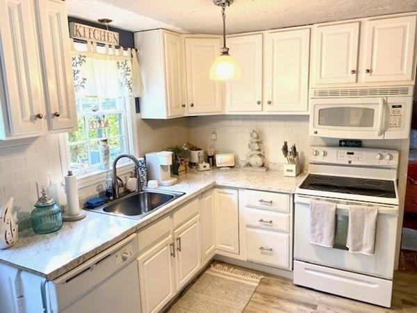 a kitchen with white cabinets white stainless steel appliances and sink