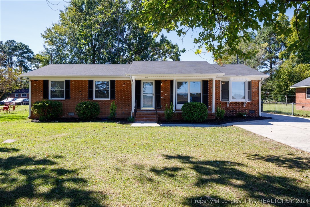 a front view of house with yard and trees in the background