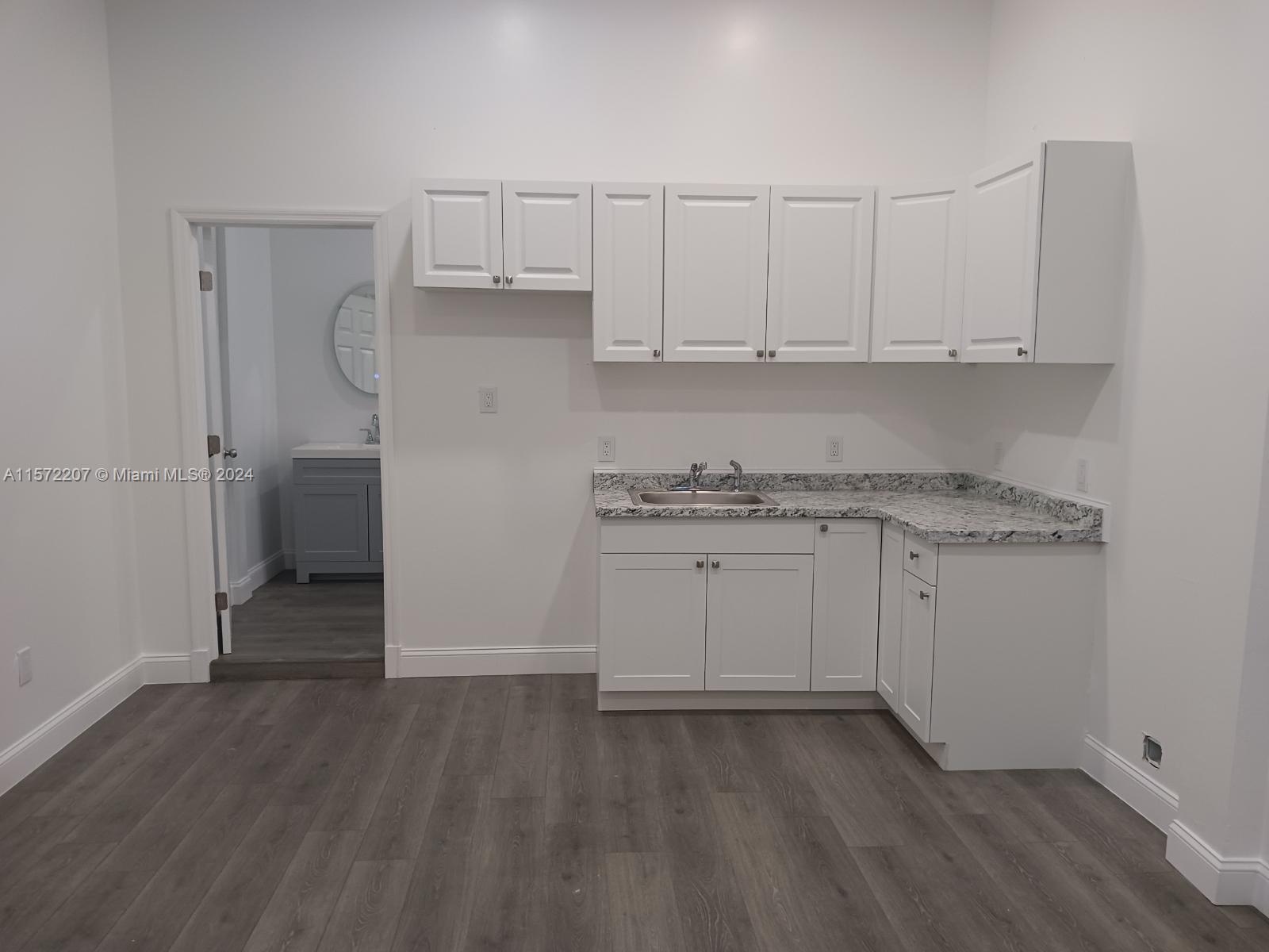 a kitchen with granite countertop white cabinets and white appliances