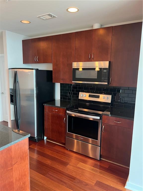 a kitchen with stainless steel appliances wooden cabinets and a stove top oven