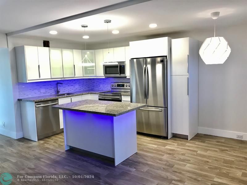 a kitchen with stainless steel appliances granite countertop a refrigerator a stove and a wooden floors