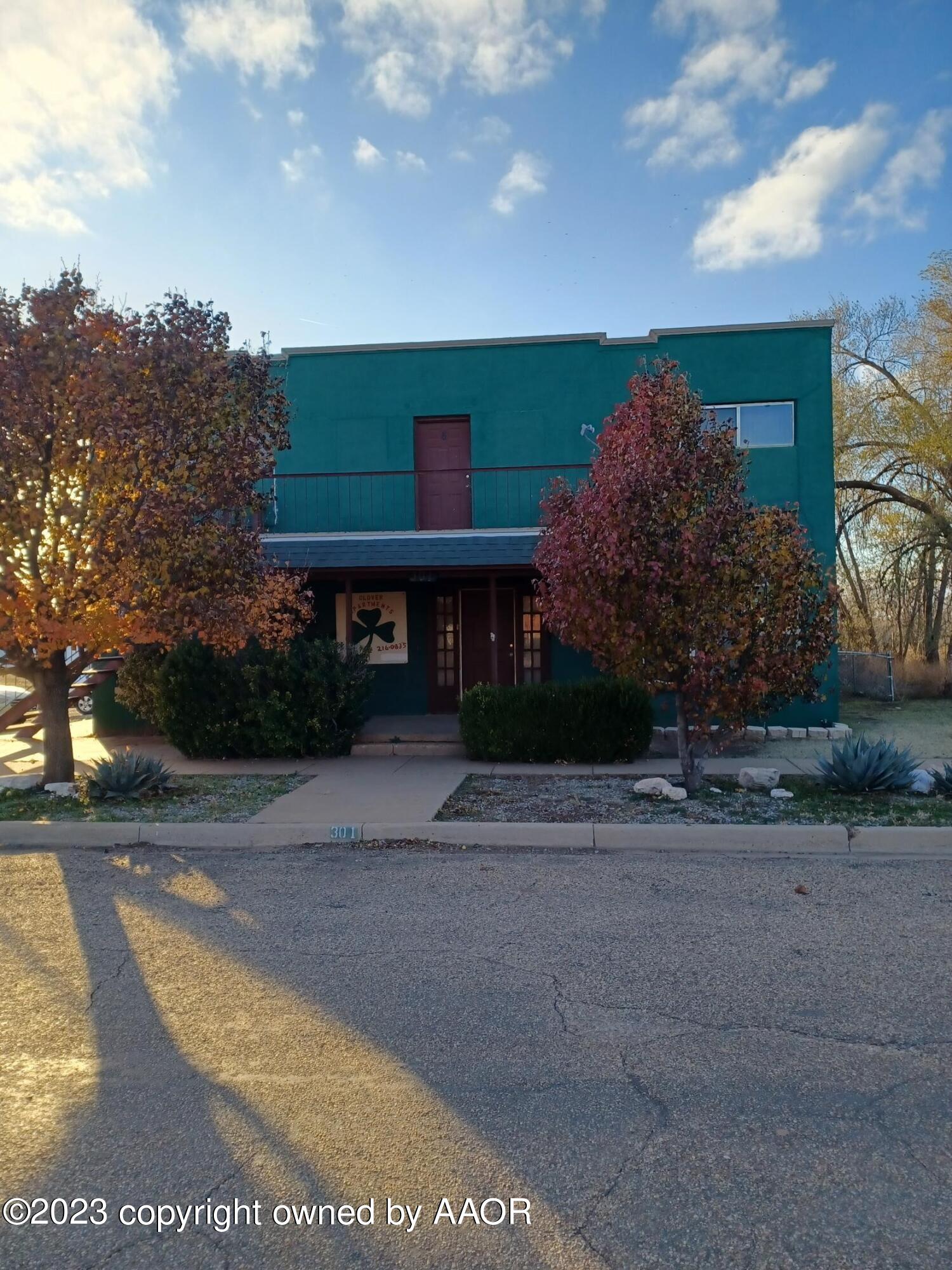 a view of a brick house next to a yard with big trees