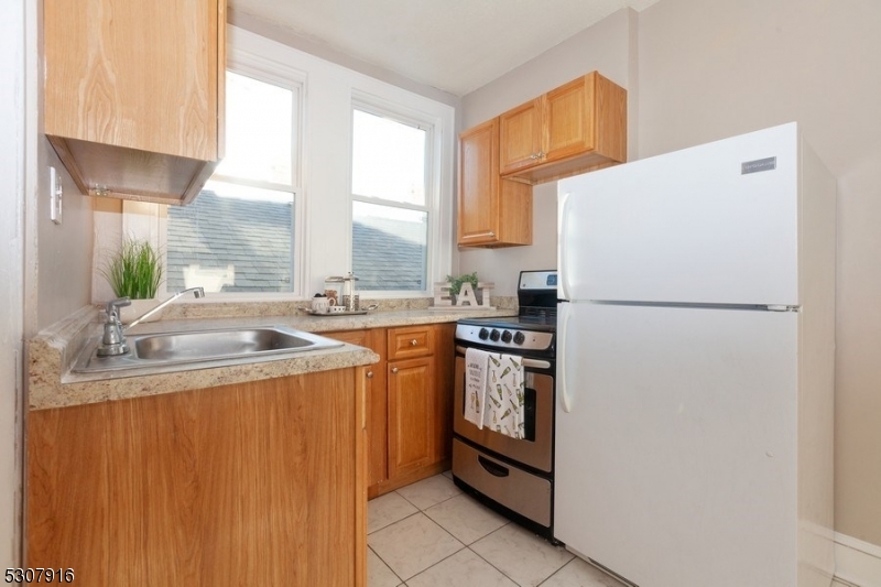 a kitchen with stainless steel appliances granite countertop a refrigerator a sink a stove and white cabinets