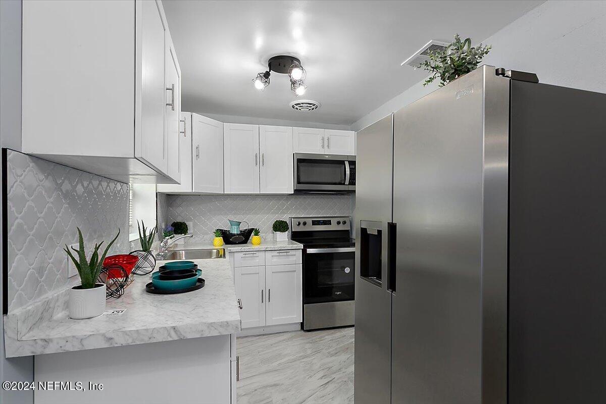 a kitchen with stainless steel appliances granite countertop a refrigerator sink stove and cabinets