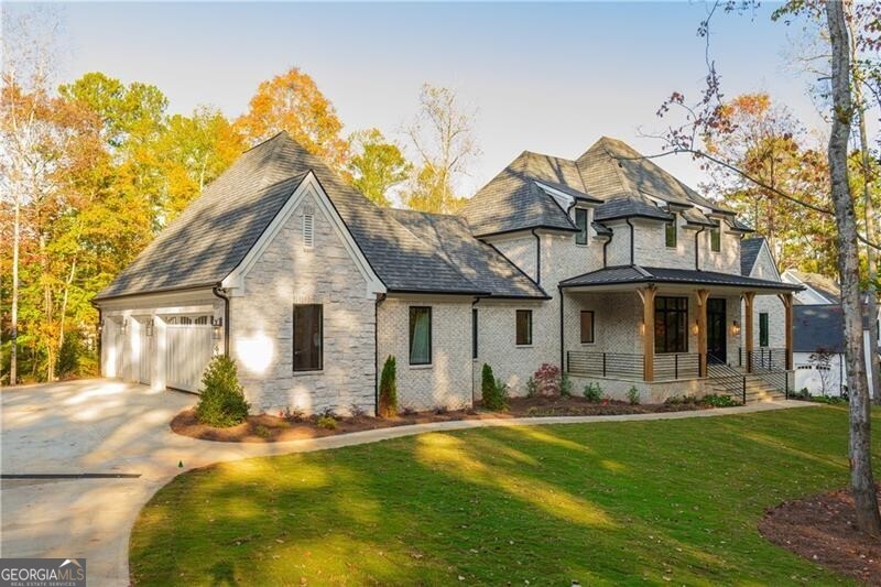 View of front of property with covered porch, a garage, and a front lawn