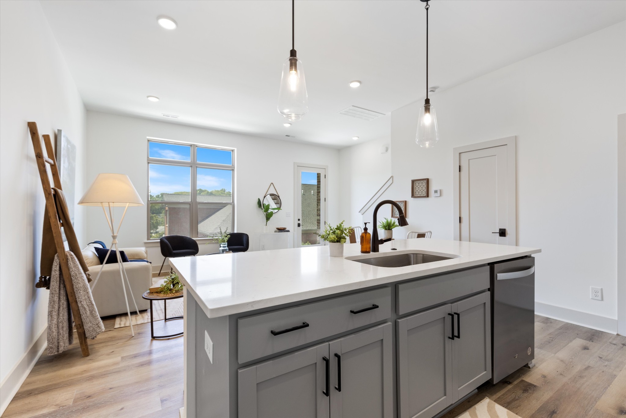 Tall ceilings with tons of light stream into this open concept living area. Quartz countertop island with under-counter sink enhances is the perfect setup for entertaining.