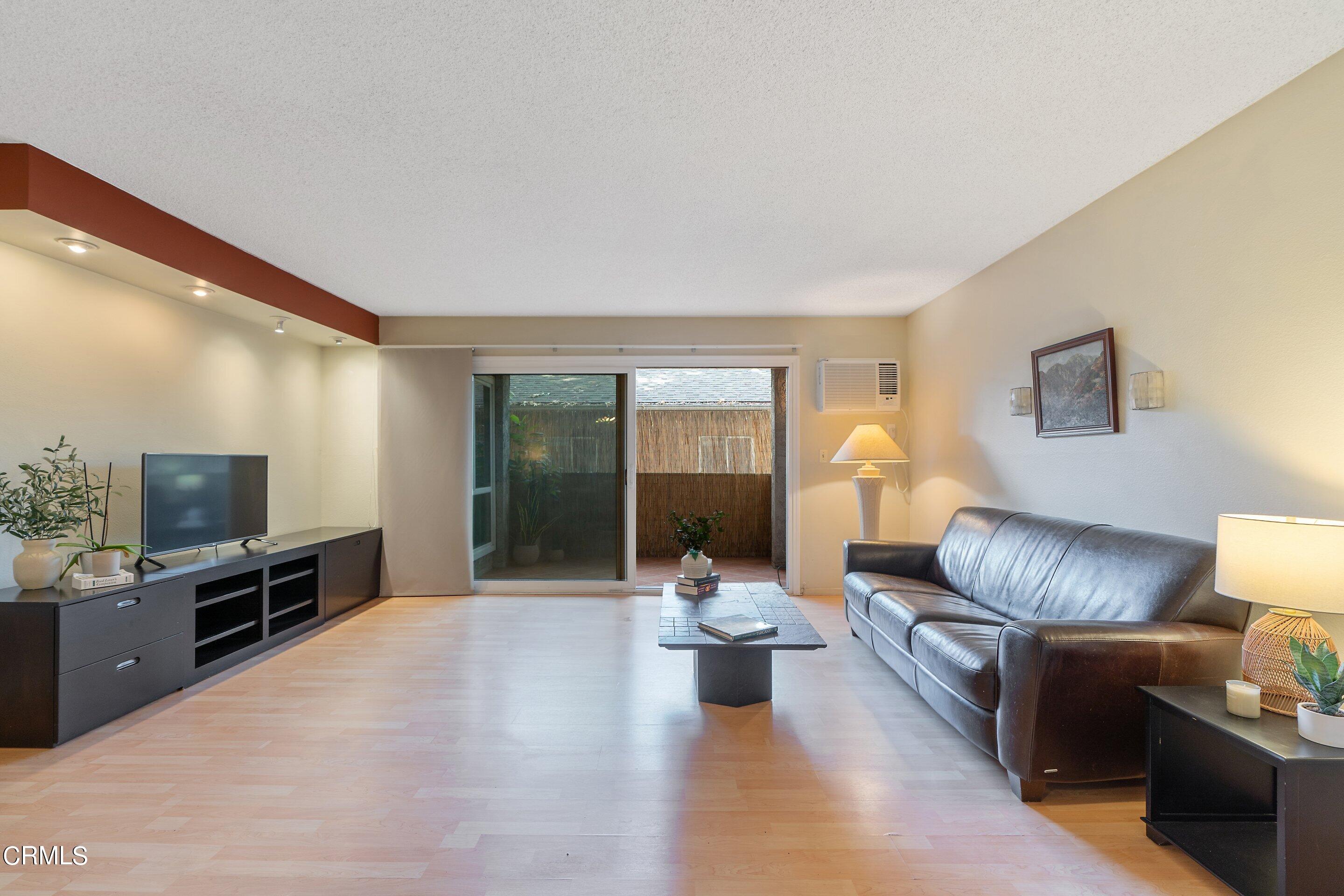 a living room with furniture a flat screen tv and a large window