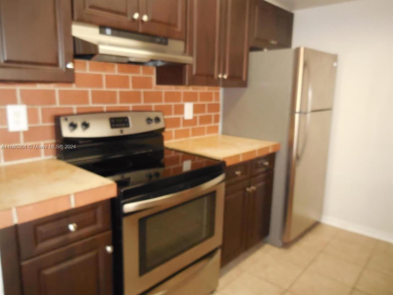 a kitchen with stainless steel appliances wooden cabinets and a stove top oven