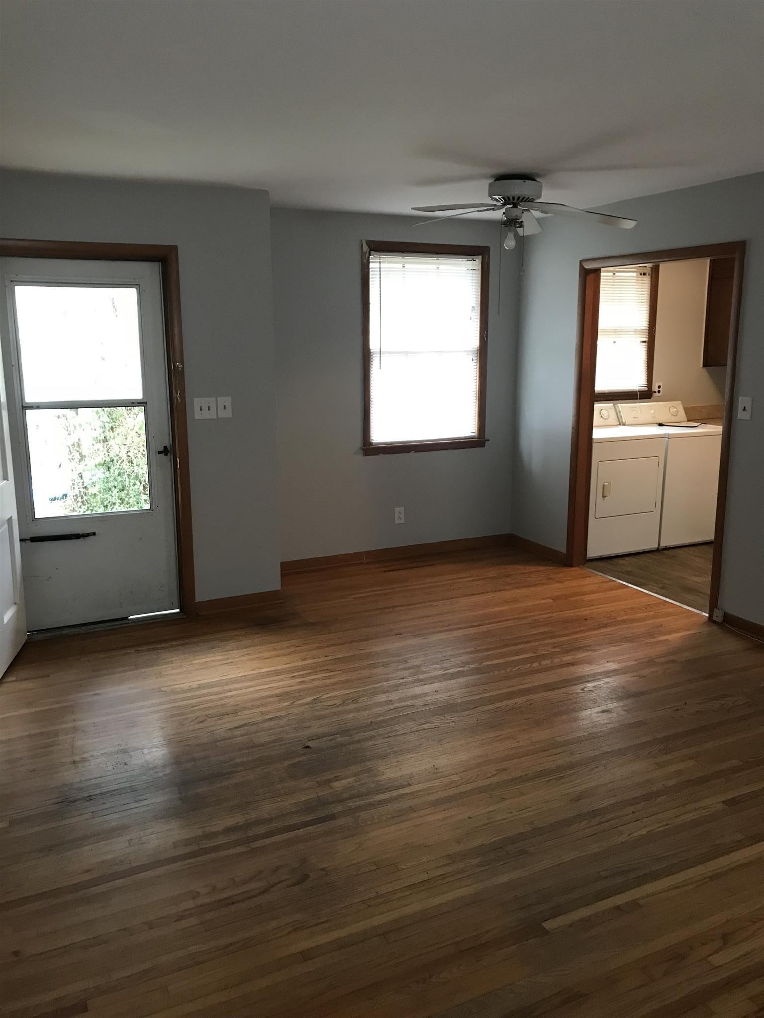 an empty room with wooden floor cabinet and windows