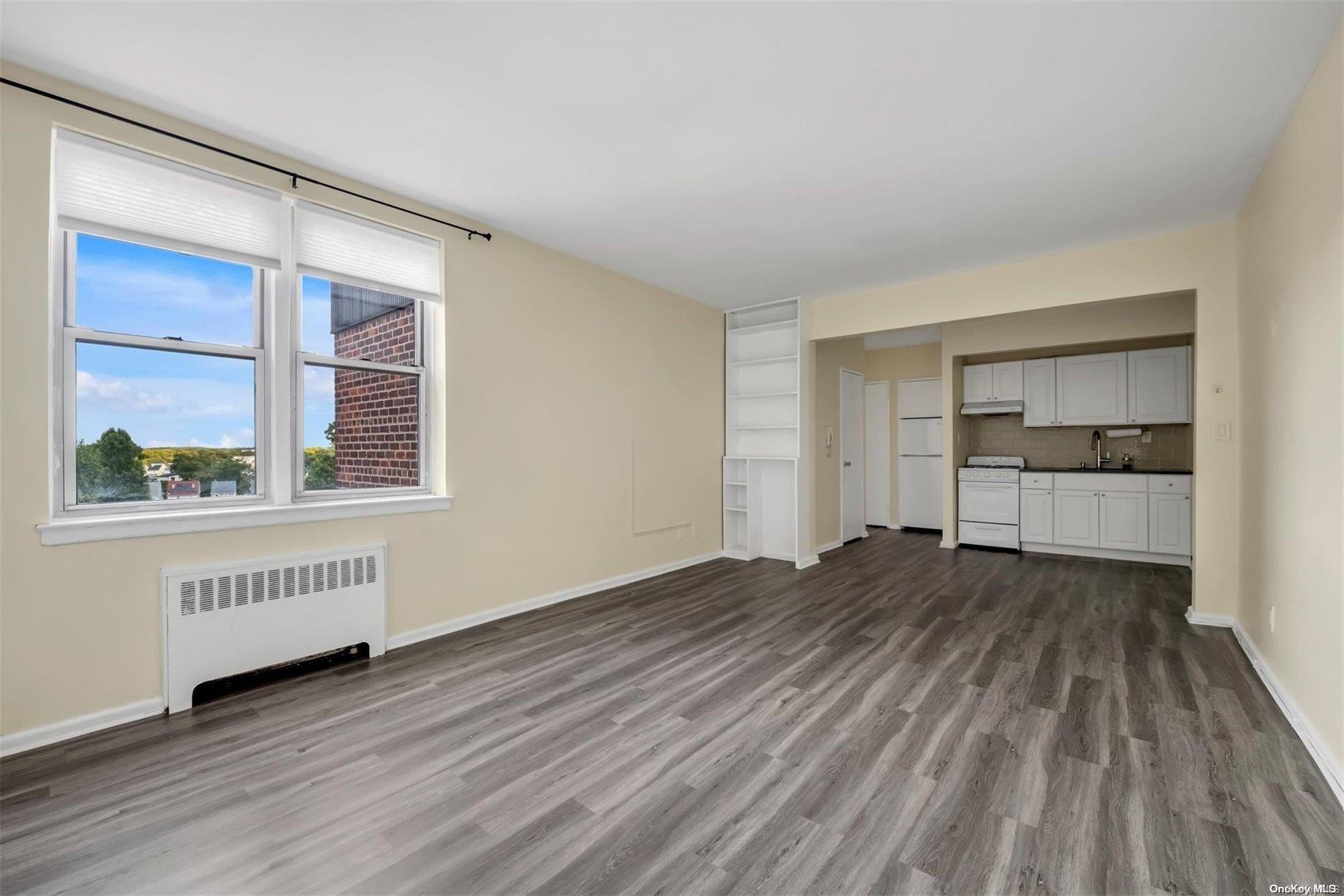 a view of an empty room with a window and wooden floor