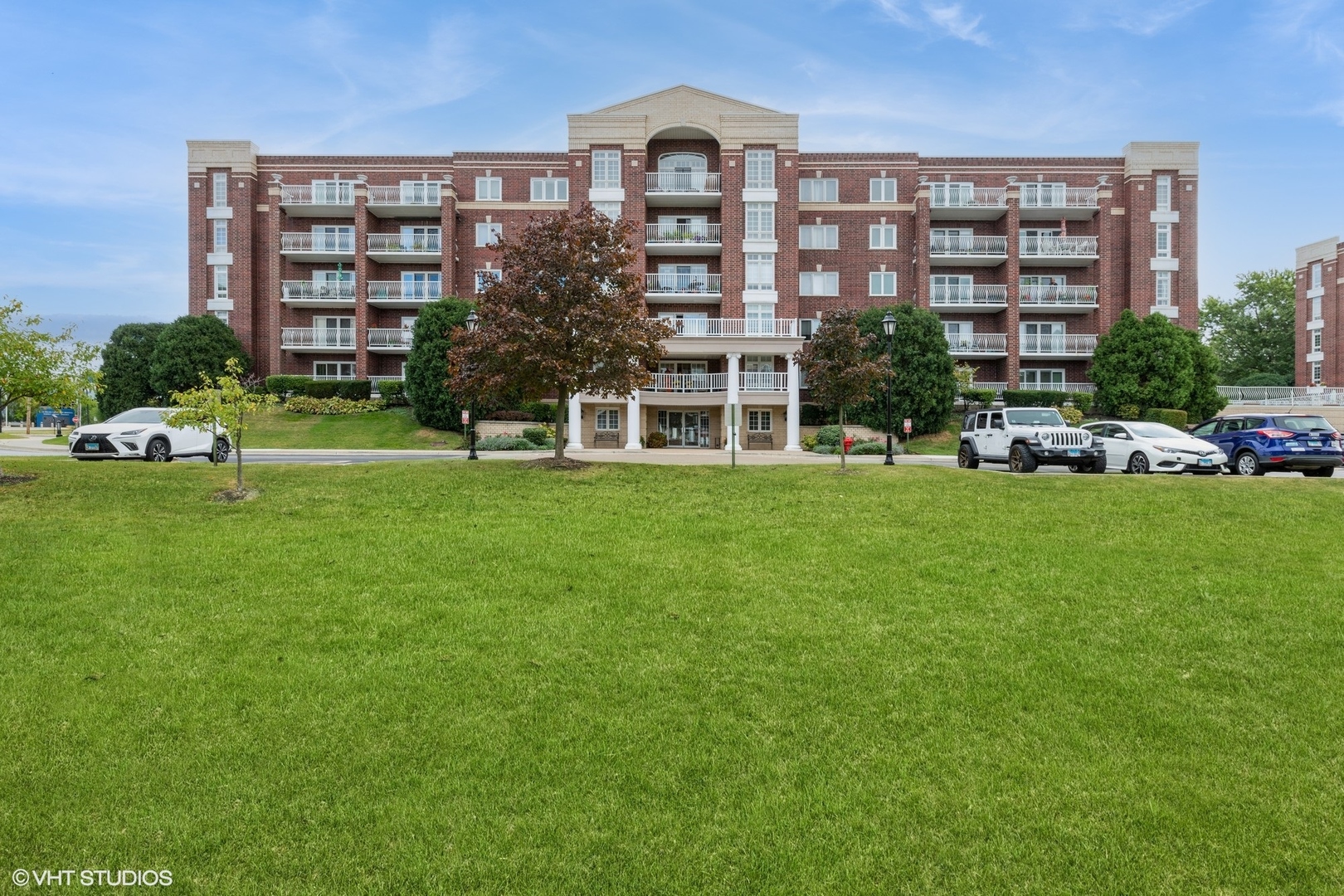 a view of a building next to a big yard and large trees