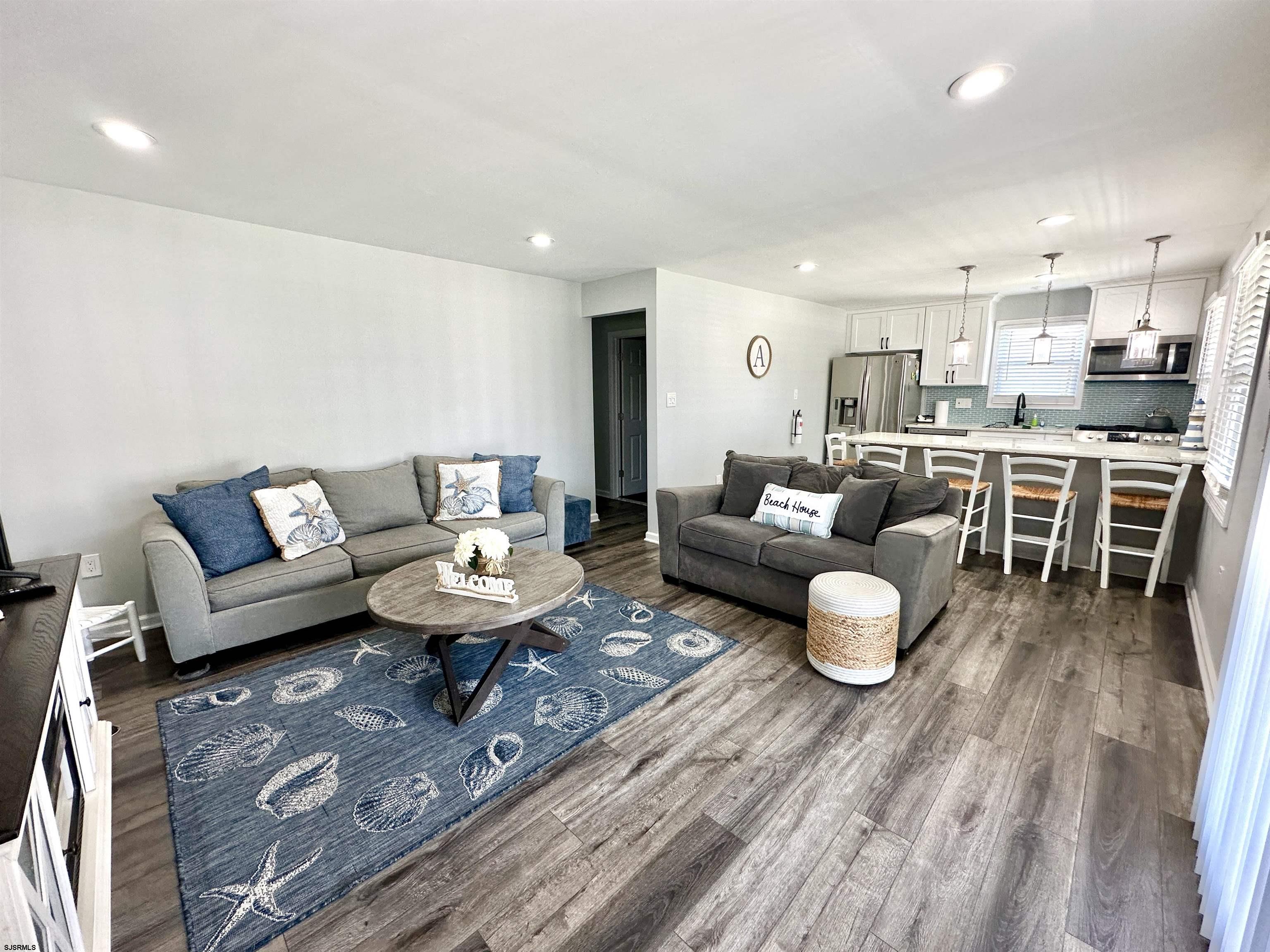 a living room with furniture and a dining table with wooden floor