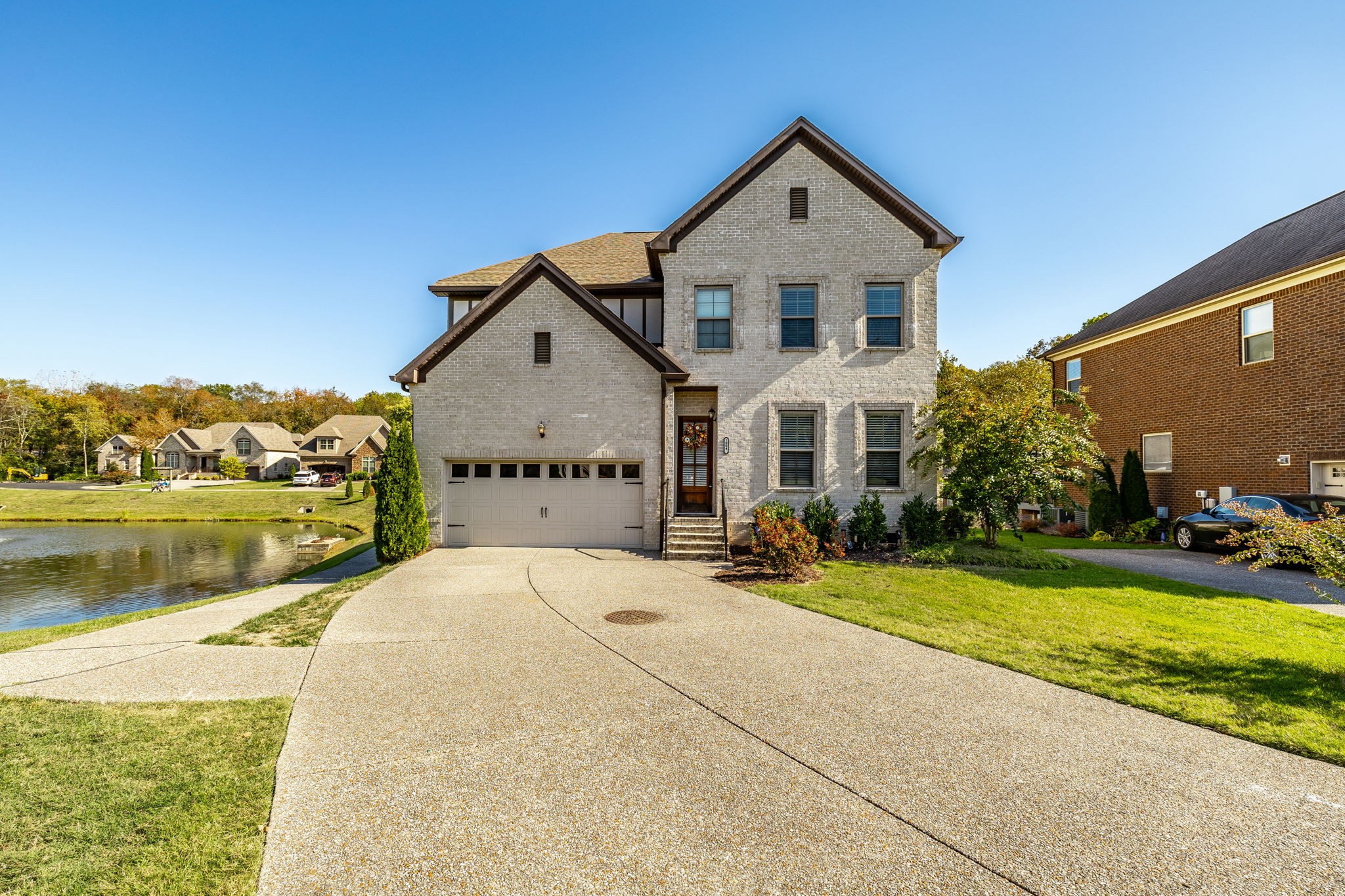 a front view of a house with a yard and lake view