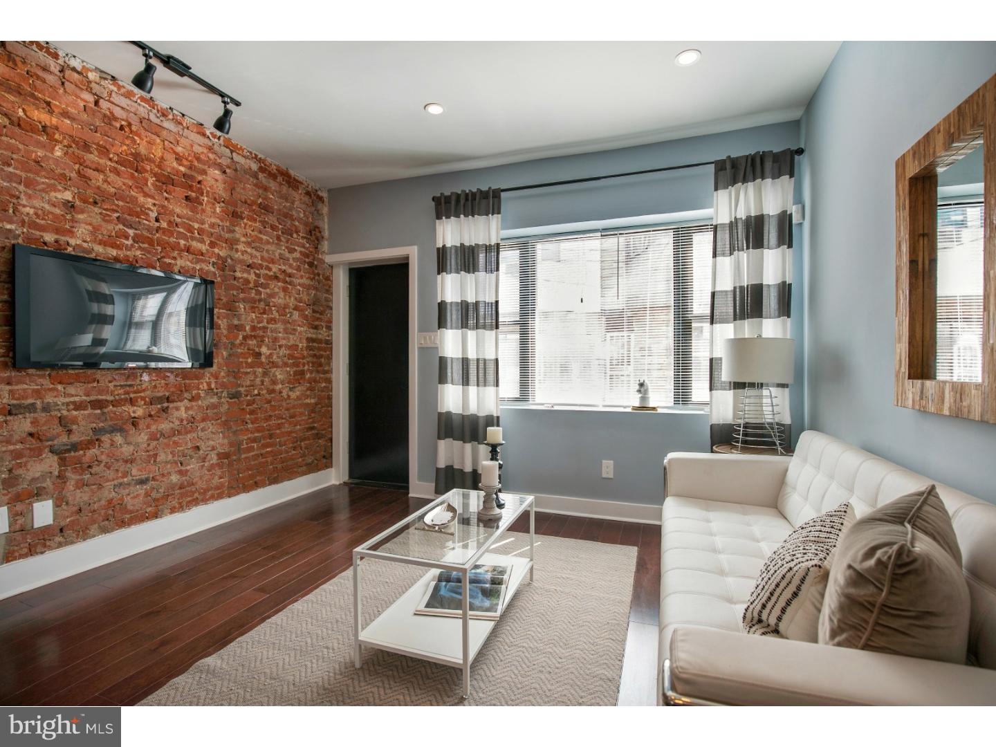 a living room with furniture a flat screen tv and a floor to ceiling window