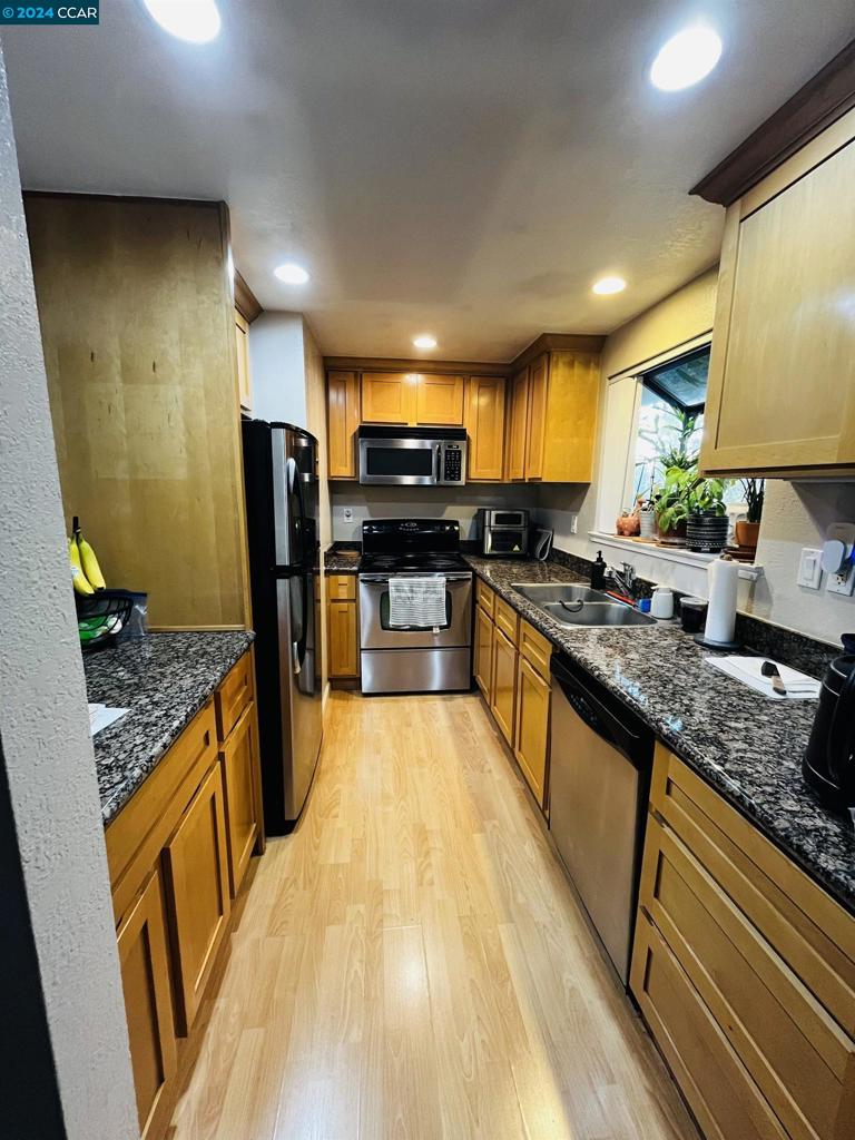 a large kitchen with stainless steel appliances granite countertop a stove a sink dishwasher and a refrigerator