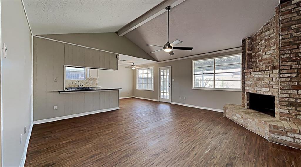 a view of a kitchen and an empty room with a fireplace