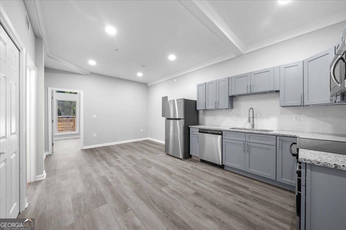 a kitchen with stainless steel appliances granite countertop a refrigerator sink and wooden cabinets