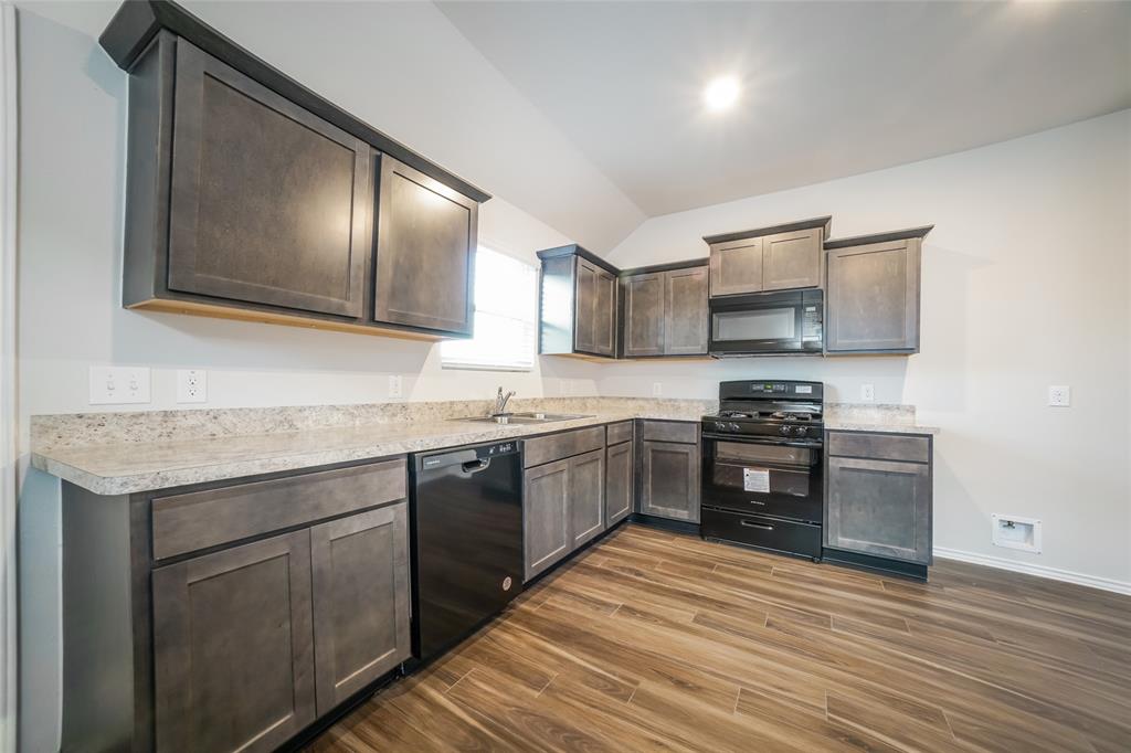 a kitchen with granite countertop a stove top oven and cabinets