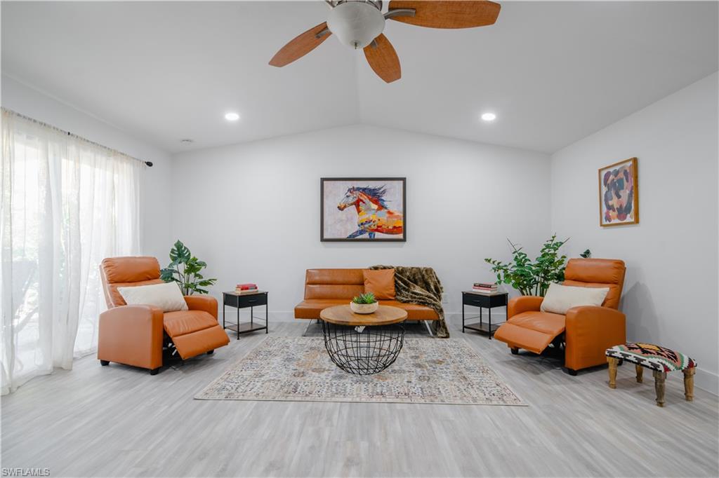 Living room featuring light wood-type flooring, ceiling fan, and lofted ceiling