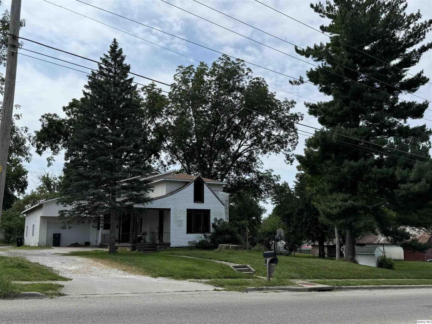 a front view of a house with a garden and trees