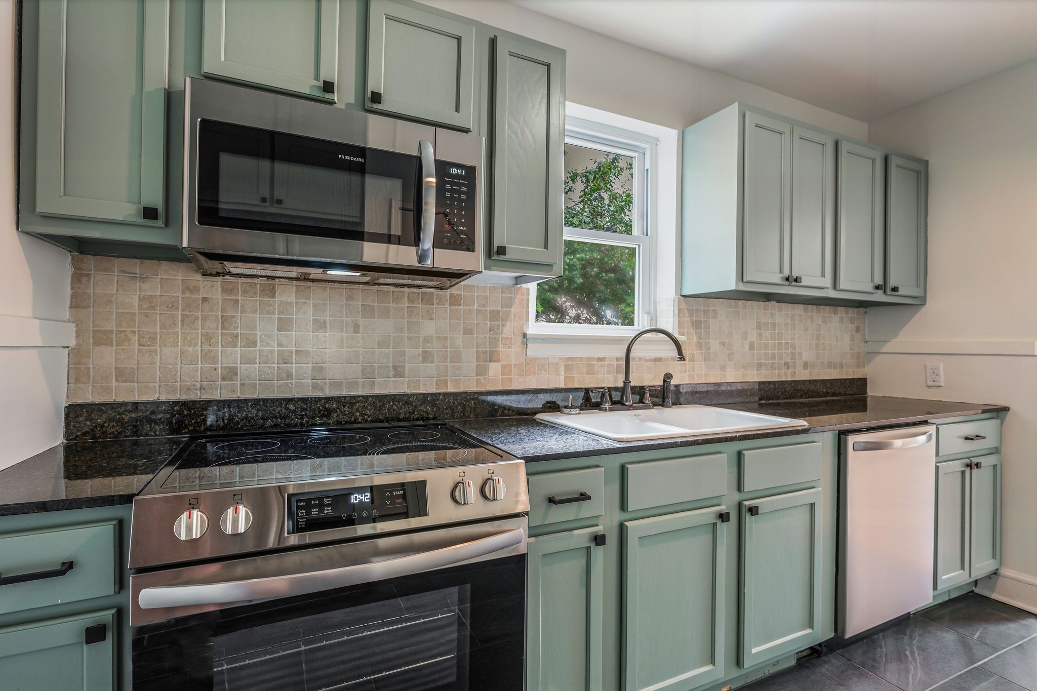 a kitchen with stainless steel appliances granite countertop white cabinets and a stove top oven