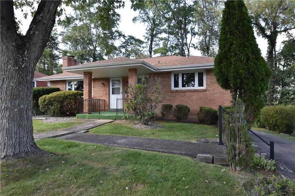 a view of a yard in front of a brick house with large windows