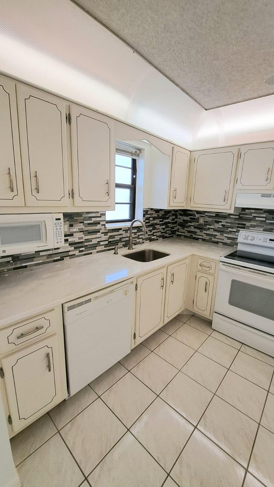 a kitchen with granite countertop white cabinets and white appliances