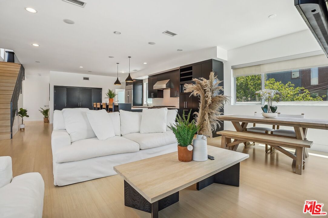 a living room with furniture potted plant and kitchen view