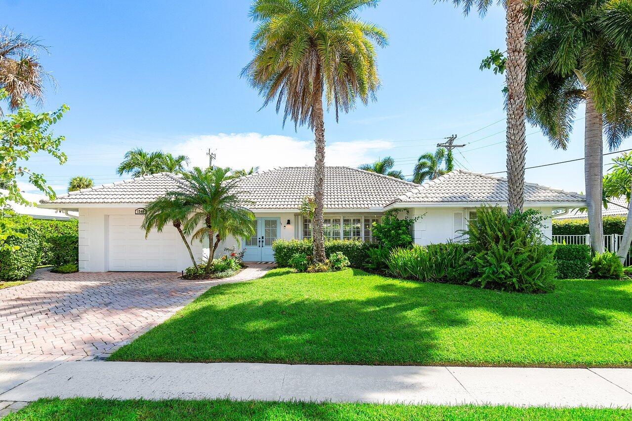 a palm tree sitting in front of a house with a yard