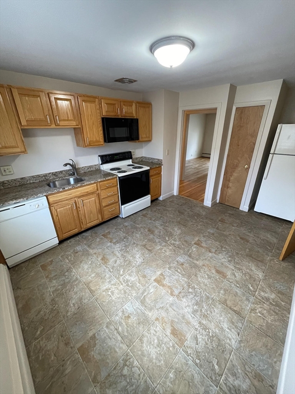 a large white kitchen with a stove a sink and a refrigerator