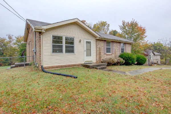 a view of house with backyard and trees in the background