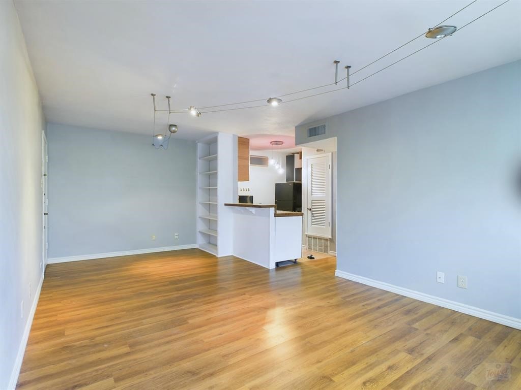 a view of kitchen and empty room with wooden floor