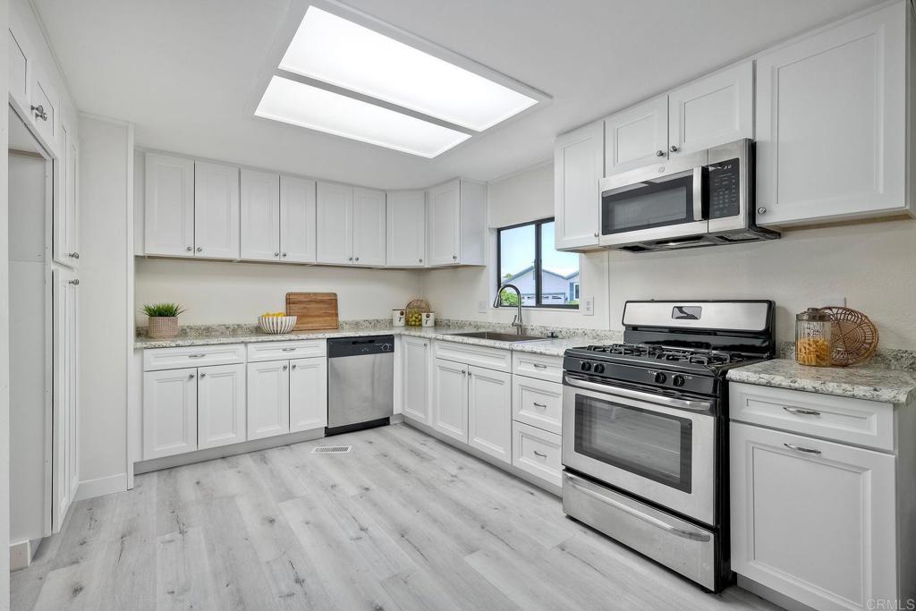 a kitchen with stainless steel appliances granite countertop a stove a sink and white cabinets