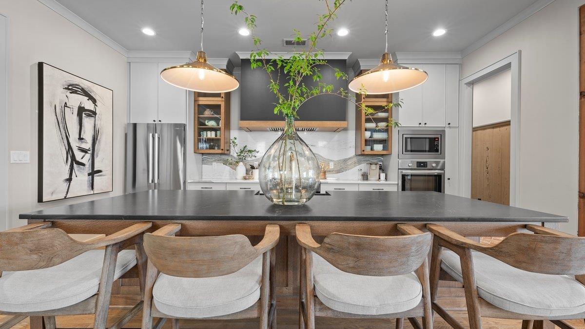 a kitchen with stainless steel appliances granite countertop a dining table chairs and a refrigerator