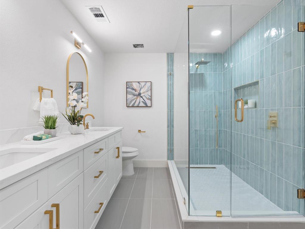 a spacious bathroom with a double vanity sink toilet and shower