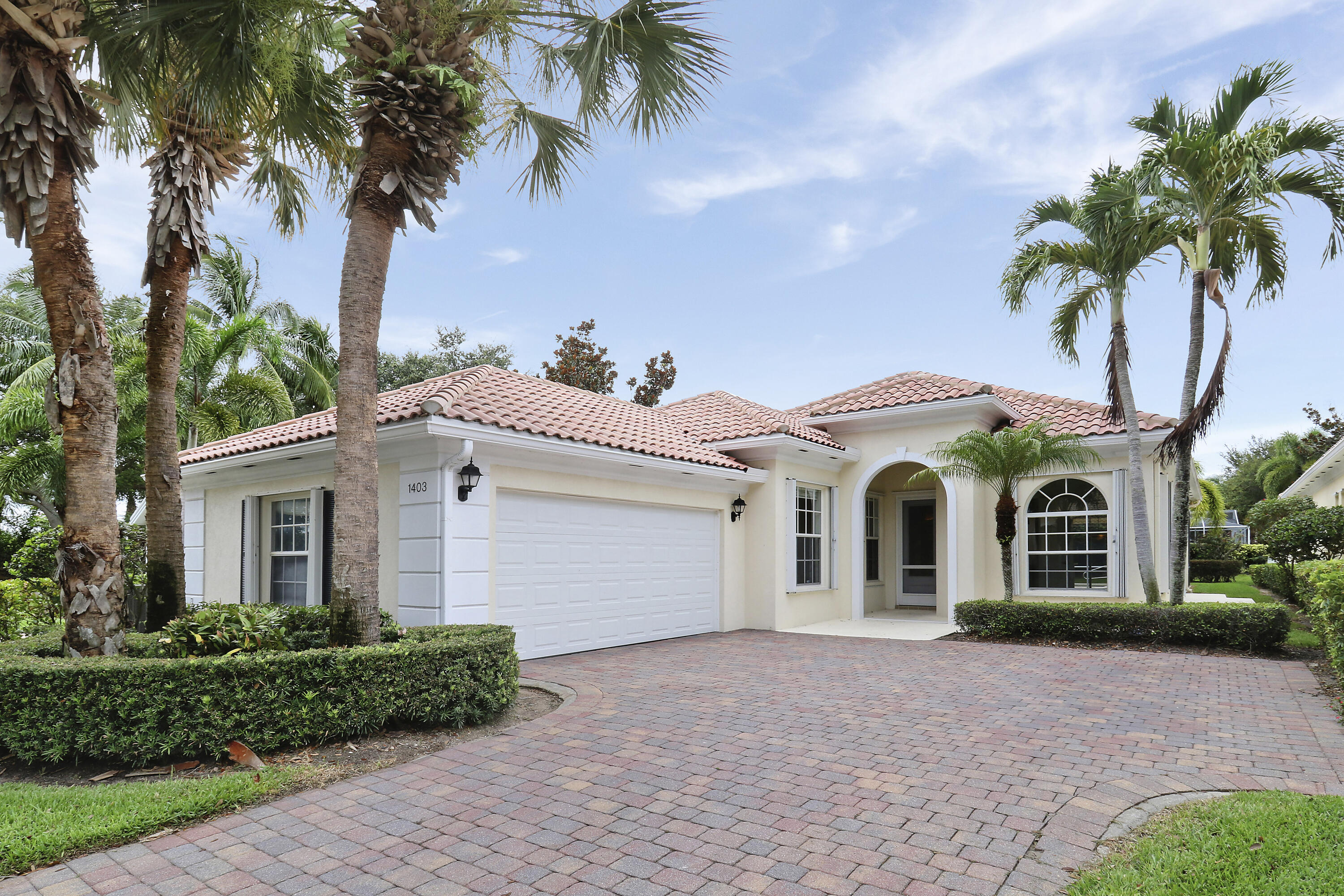 a view of a white house with a yard and palm trees