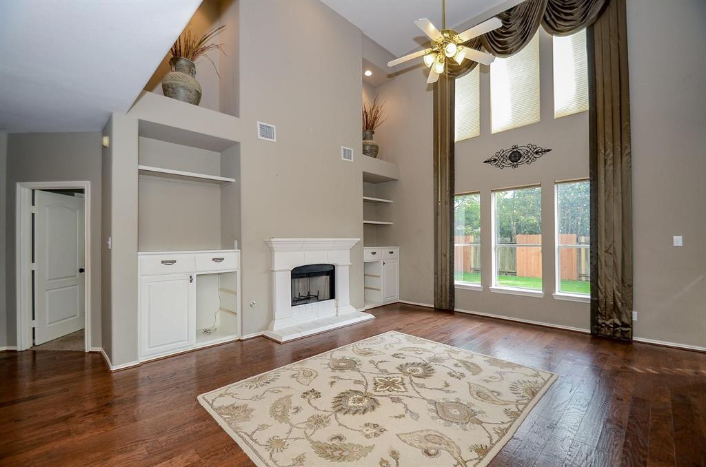 a view of a livingroom with wooden floor a fireplace and windows