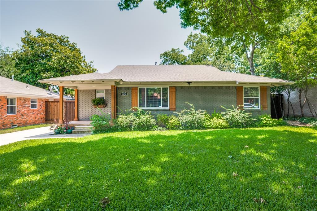 a front view of a house with a yard and potted plants