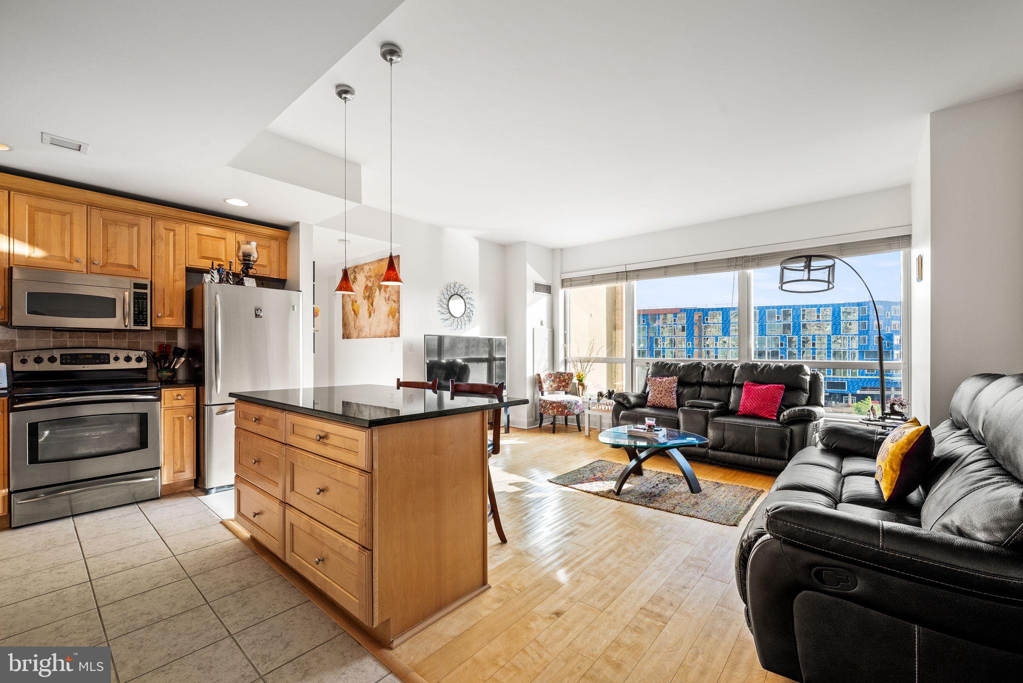 a living room with stainless steel appliances furniture cabinets and a kitchen view