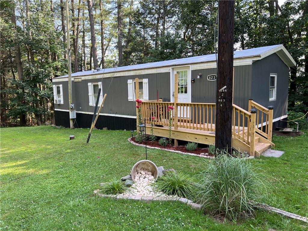 Front view of property with a lawn and a wooden deck