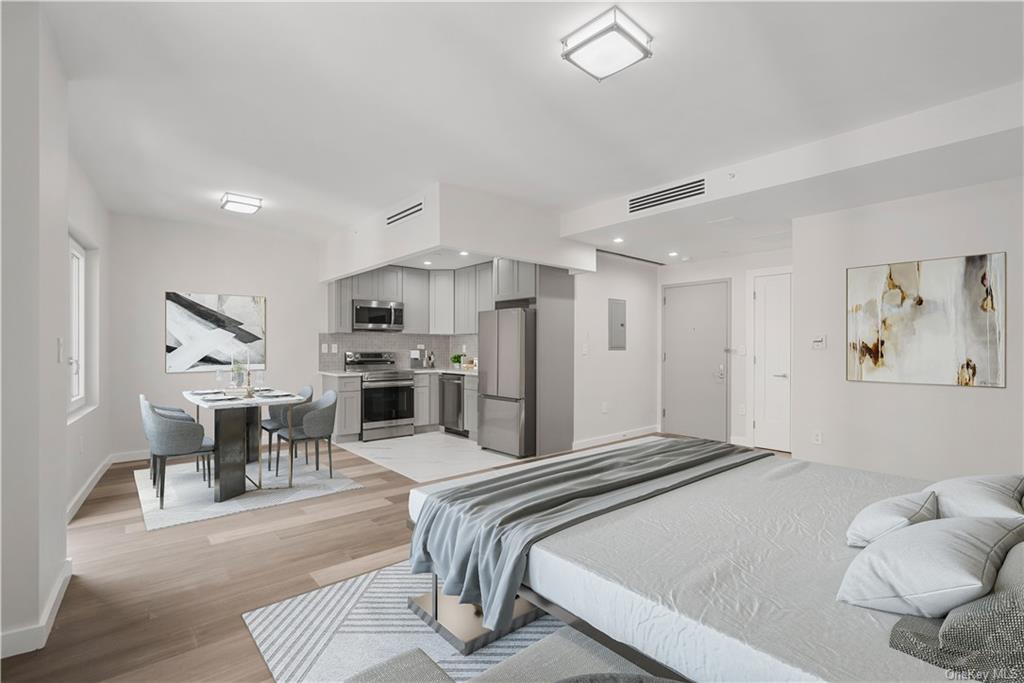 Bedroom with light wood-type flooring and stainless steel refrigerator