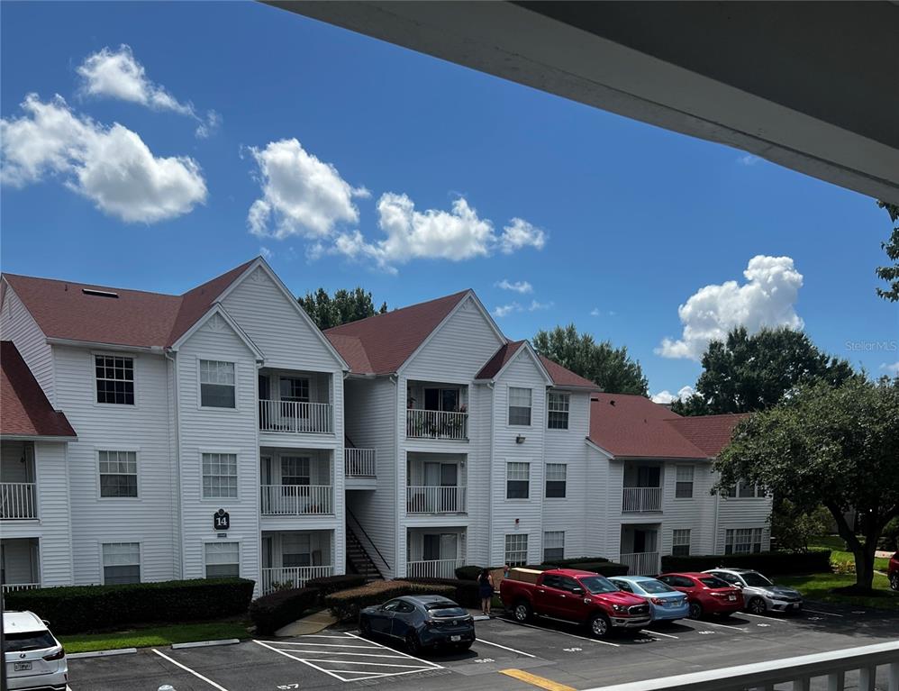 a front view of a building with lot of cars and trees