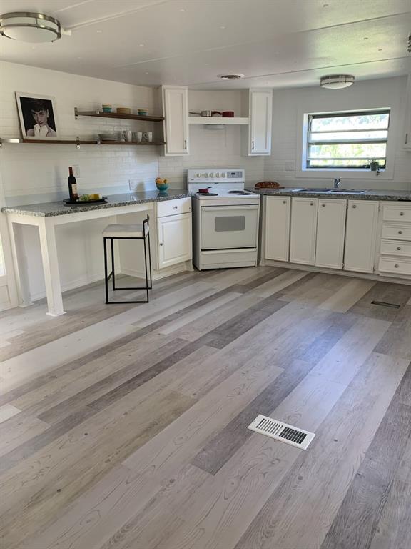 a kitchen with cabinets wooden floor and stainless steel appliances