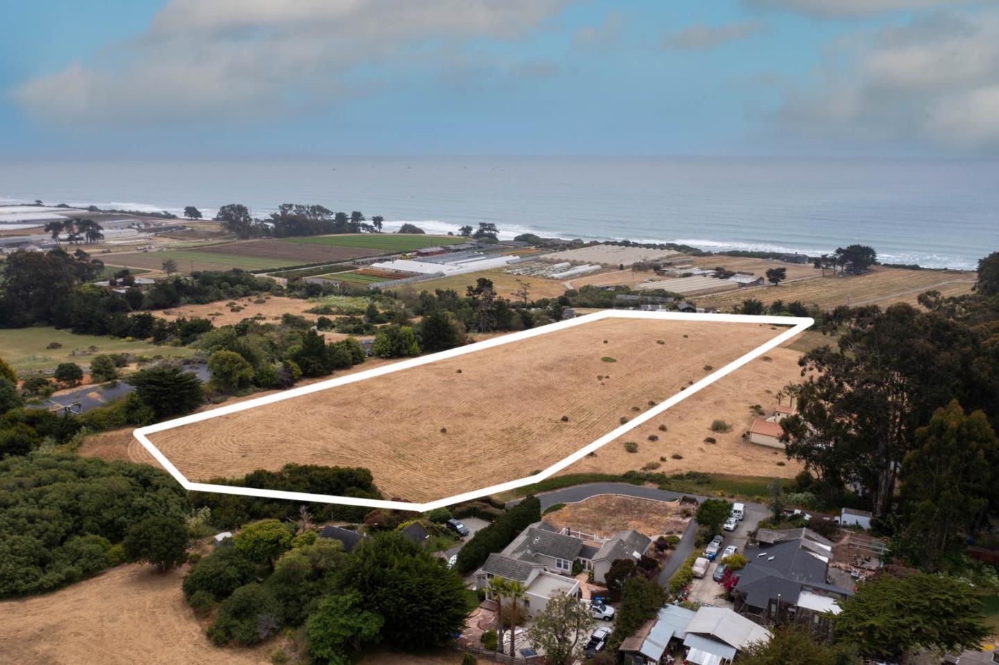 an aerial view of ocean and residential houses with outdoor space