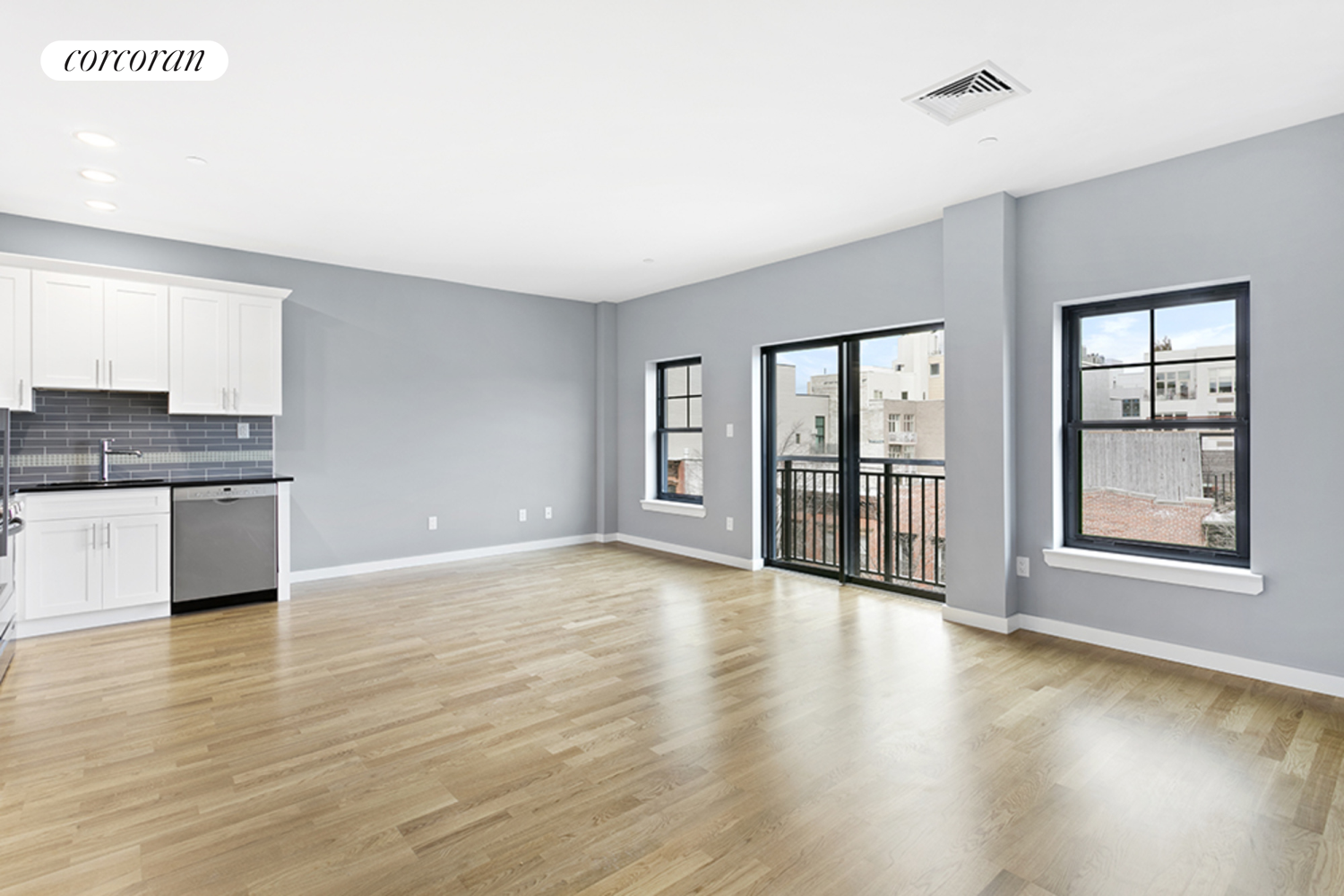 a view of an empty room with window and wooden floor