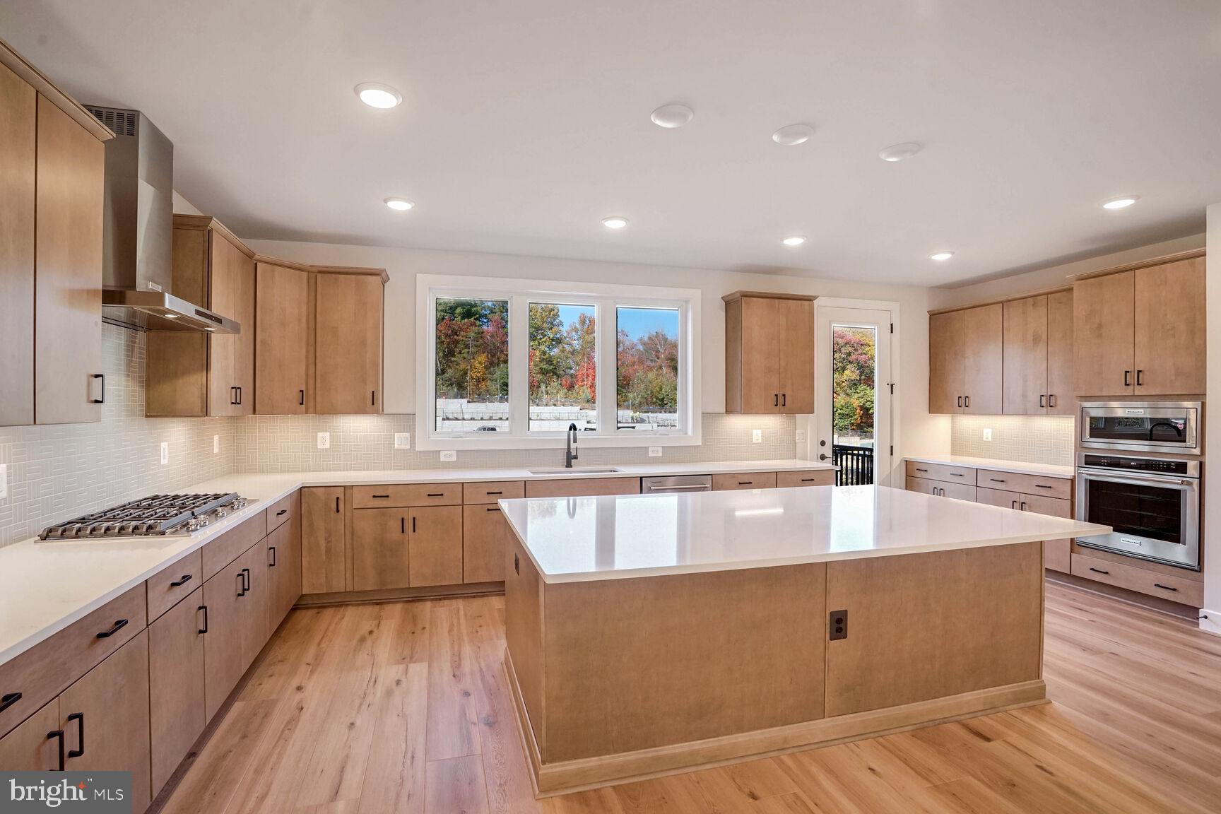 a large kitchen with granite countertop a large counter top stainless steel appliances and cabinets