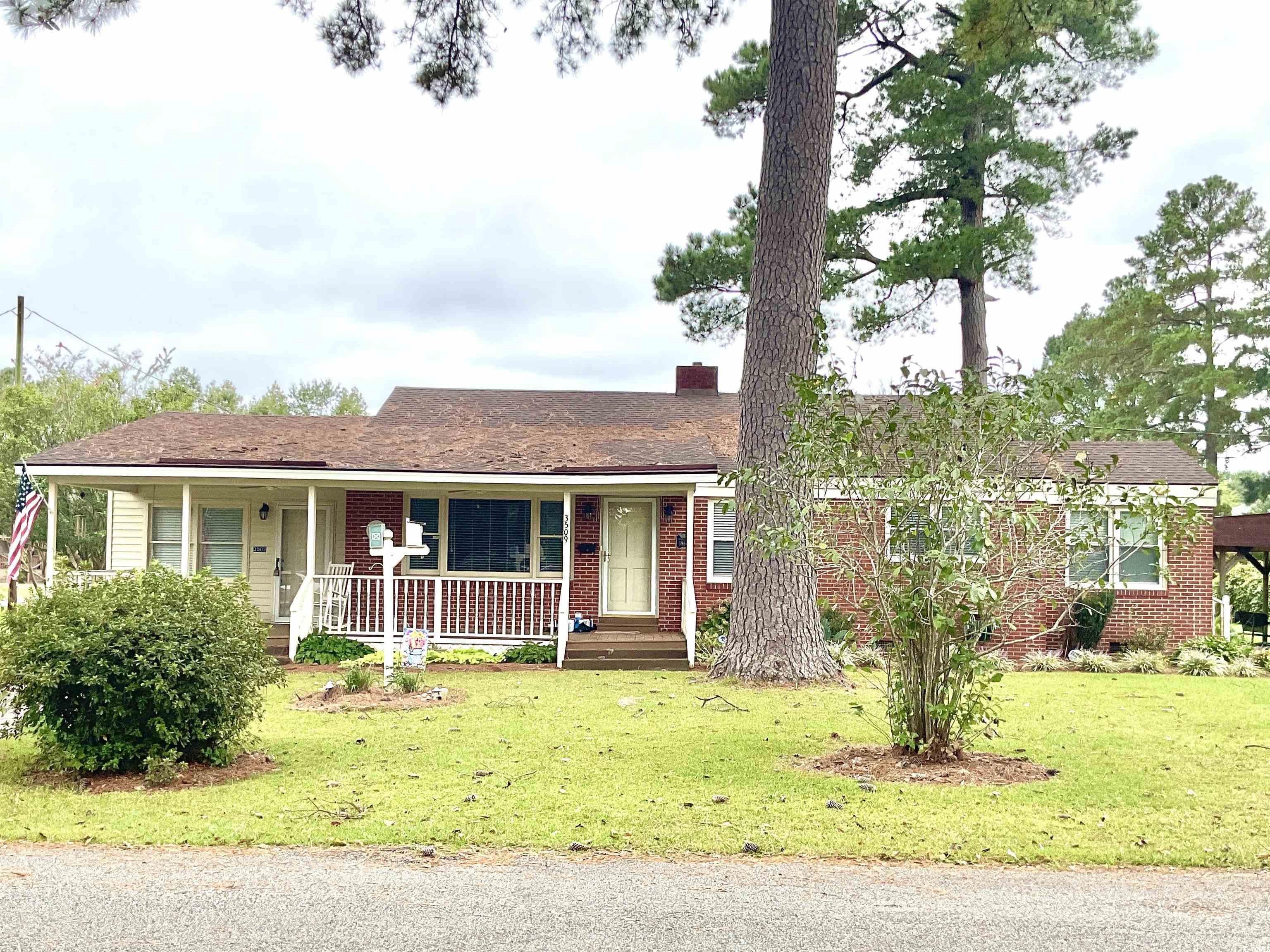 Ranch-style house featuring a porch and a front la